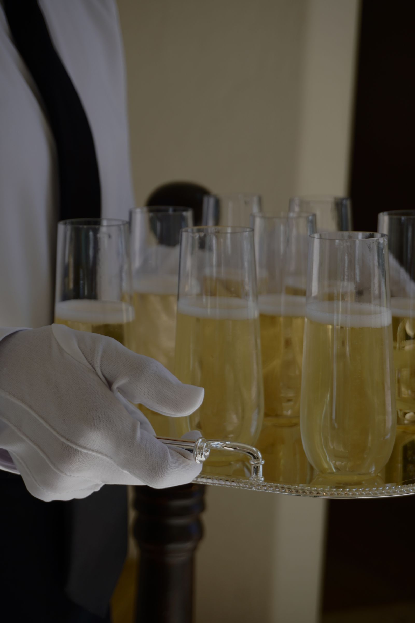 White-glove staff pouring champagne from a silver tray