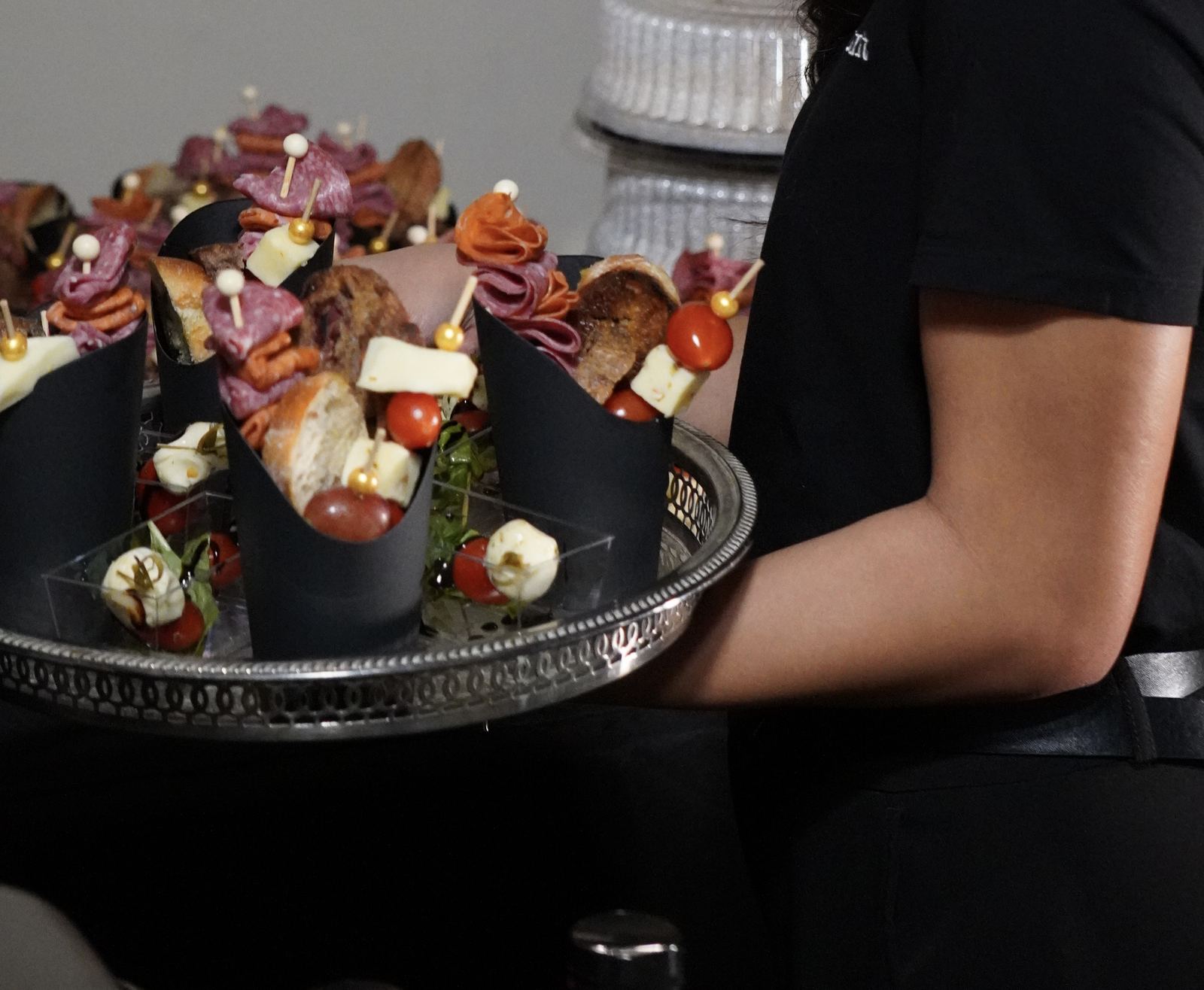 Shaken Entertainment server passing charcuterie cups on a silver tray